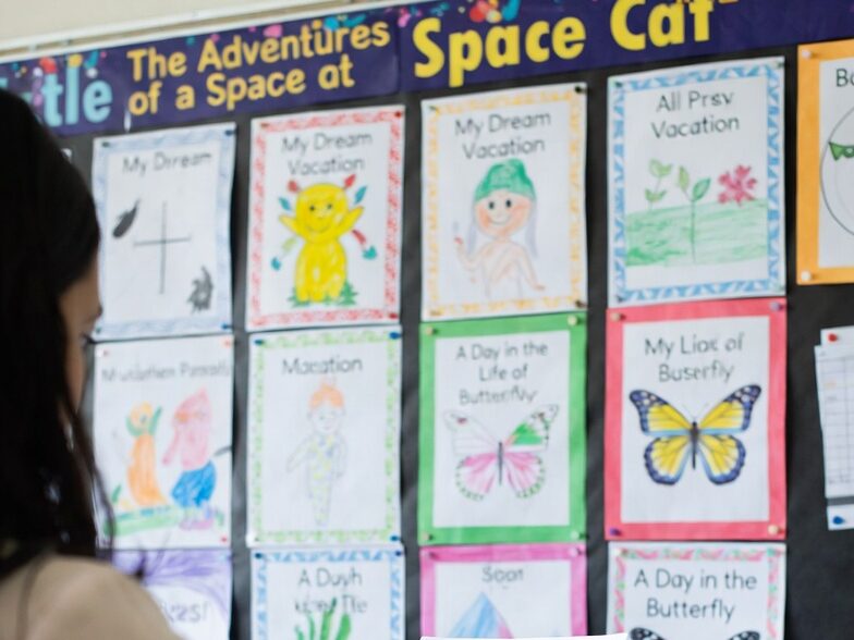 Bulletin Board Display of Student Writing
A colorful classroom bulletin board showcasing student compositions with creative titles, highlighting diversity in topics and voices.