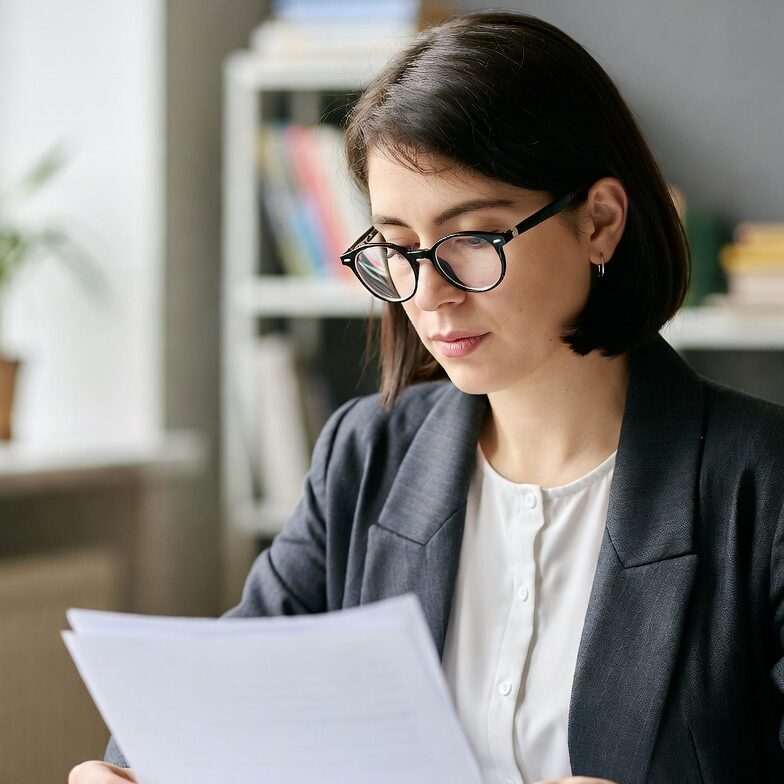Teacher Reviewing Student Work
A teacher sitting at a desk with a stack of papers, reading a student’s handwritten composition with a pen in hand, emphasizing feedback and trust.